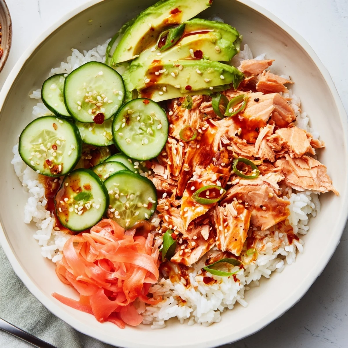Leftover Salmon & Rice Bowl topped with fresh avocado and vibrant cucumber slices.  