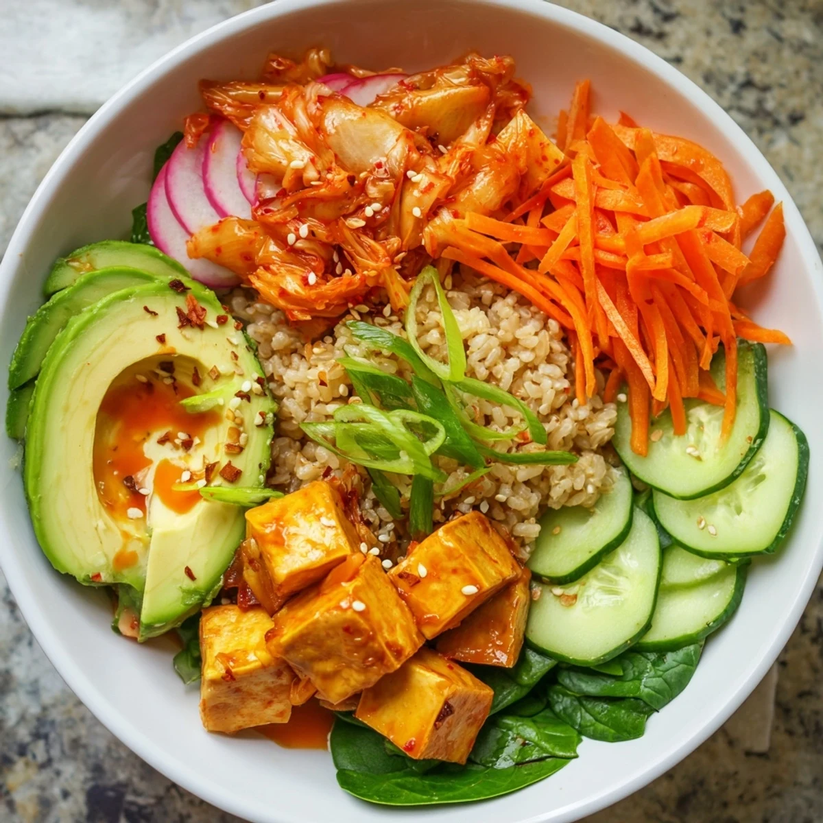 Colorful fermented vegetable bowl with tangy kimchi, topped with avocado slices and sesame seeds.  