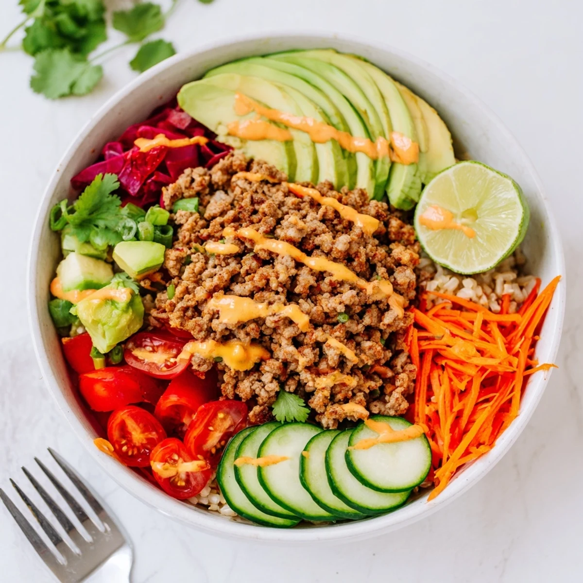 Vibrant plant-based meat bowl topped with fresh veggies and zesty lime wedges.  