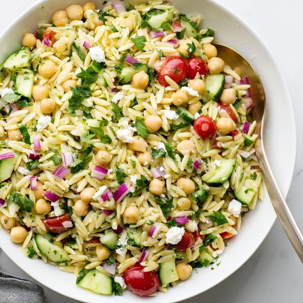 Freshly tossed Lemony Chickpea Orzo Salad featuring chickpeas, diced veggies, and herbs drizzled with lemon vinaigrette.