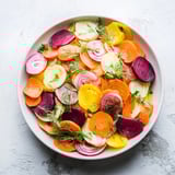 Freshly assembled "Spinning Top" salad, showcasing colorful ribbons and a bright herb garnish.