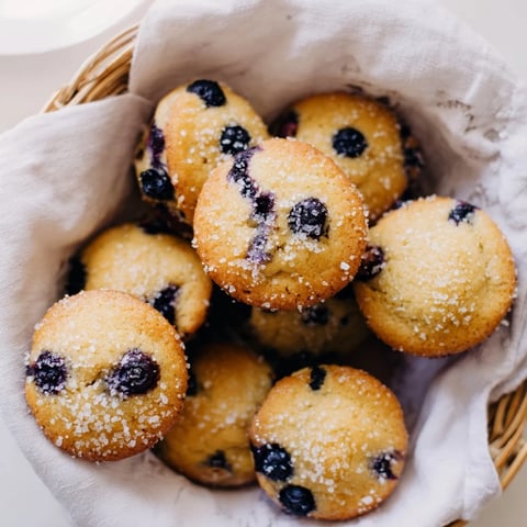 Fluffy mini blueberry muffins in a basket, perfect for a delightful brunch spread, fresh from the oven.
