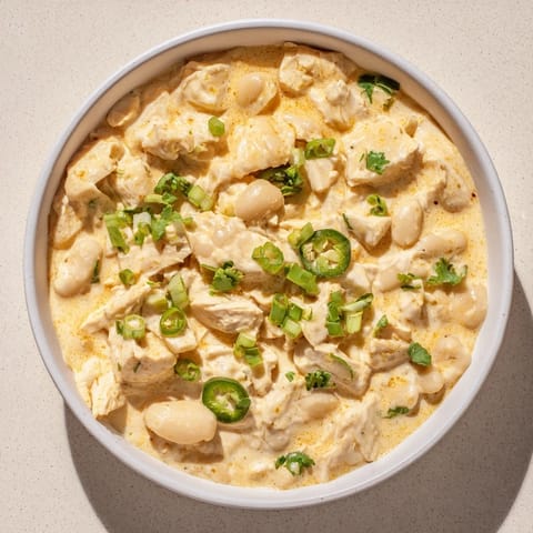 Spoonful of creamy white chicken chili with beans, a hearty and warming dish perfect for any evening.