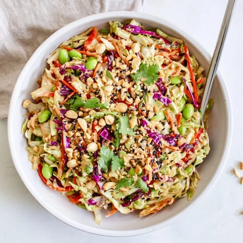 A close-up of the vibrant Crunchy Thai Peanut Salad with red bell pepper strips and fresh cilantro, ready to serve as a refreshing side.  