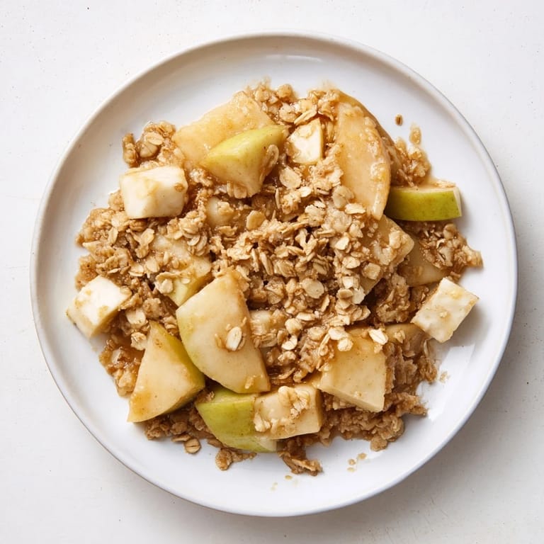 A close-up of a freshly baked Best Apple Crisp, showcasing tender apples under a crispy oat topping.