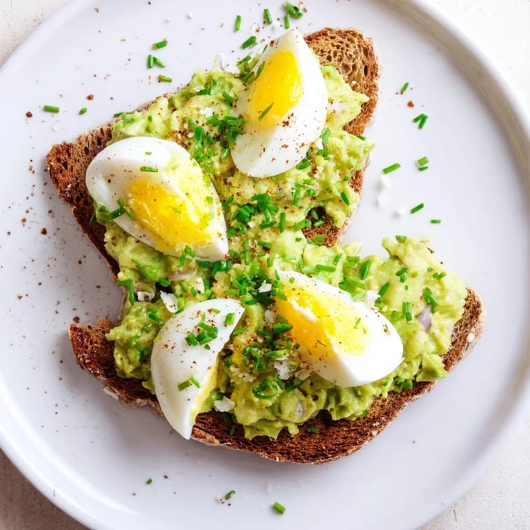 Spoonful of vibrant avocado egg smash, showing a close-up of the fresh herb sprinkle.