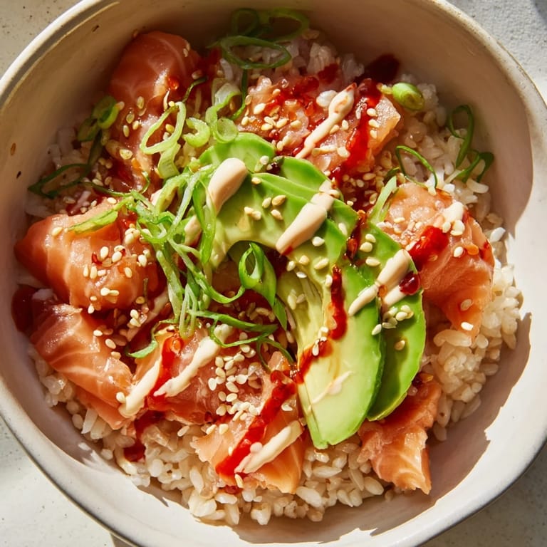 This Emily Mariko salmon rice bowl features glistening rice, spicy mayo, and toasted sesame seeds ready to eat.