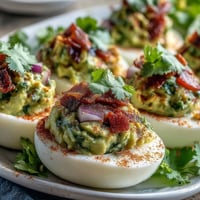 Creamy guacamole stuffed deviled eggs with avocado filling, lime, and a hint of spice for a fresh appetizer twist.  